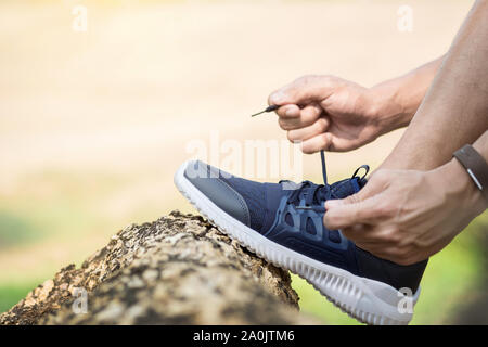 Schuss des jungen Mannes Läufer anziehen Laufschuh Schnürsenkel, immer bereit zum Joggen Übung im freien beschnitten. Männliche Jogger Schnürung Sneaks stehend Stockfoto