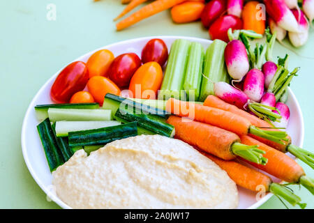 Frisches Gemüse Gemüsestäbchen Platte mit Hummus und Karotten, Radieschen, Gurken, Sellerie und Tomaten/Paradeiser Stockfoto