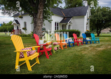 Bunte Garten Stühle hinzufügen Kontrast und Interesse zu einem ländlichen Haus und Hof. Stockfoto