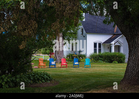 Bunte Garten Stühle hinzufügen Kontrast und Interesse zu einem ländlichen Haus und Hof. Stockfoto