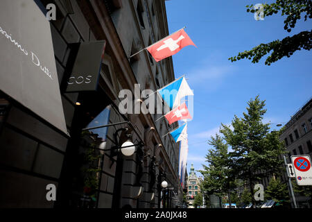 Zürich, Schweiz, 19. Juli 2019: Nationale Fahnen von Zürich und der Schweiz auf einer modernen COS Gebäude gegen den blauen Himmel, Ansicht, Straße an einem sonnigen Tag Stockfoto