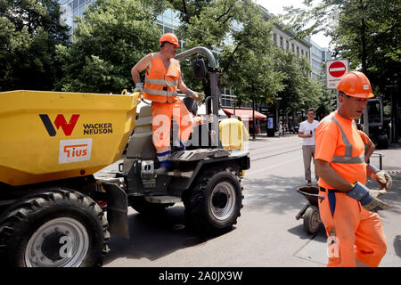 Zürich, Schweiz, 19. Juli 2019: Nahaufnahme von Beschäftigten im Straßenverkehr in orangefarbenen Anzügen mit Helmen und Erde remover Lkw auf der Straße von Zürich sonnigen Tag gekleidet Stockfoto