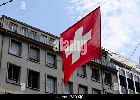 Flagge der Schweiz hängen an mitten auf der Straße mit dem Bau- und blauen bewölkten Himmel im Hintergrund Stockfoto