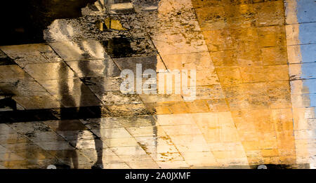 Blurry abstrakte Schatten silhouette Reflexionen von zwei Menschen zu Fuß auf nasser Straße Bürgersteig Stockfoto