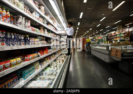 Zürich, Schweiz, 19. Juli 2019: Arbeitnehmer kletterte zu stehen und ordnet Produkte, Innenraum des Supermarkts COOP CITY in Zürich. Stockfoto