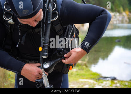 Paayanne See, Finnland - September 2019. Diver prüft Geräte in der Nähe des Sees. Männliche Taucher im Neoprenanzug überprüfen Ausrüstungen vor dem Eintauchen. Stockfoto