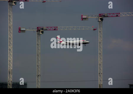 London, UK, 16. Mai 2019, BA Flugzeug in Land am London City Airport kommen, wie es zwischen Kranen aufgehängt ist, bezieht sich auf die Geschichten. Stockfoto