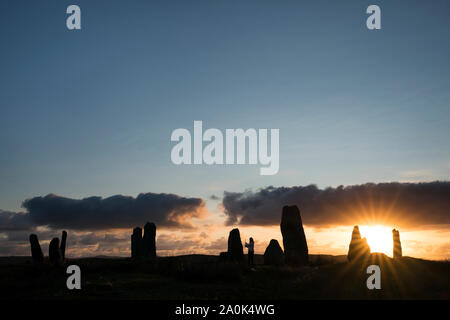 Touristische videos besuchen Sie sie bei Sonnenuntergang an den Callanish Standing Stones III vor blauem Himmel auf der Insel Lewis, Äußere Hebriden, silhouetted Scotl Stockfoto