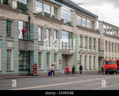 Moskau, Russland - 14. September 2019: Kletterer mit Treppen waschen Fenster im Gebäude. Arbeitnehmer in der Marke Overalls und spezielle Ausrüstung für altitud Stockfoto