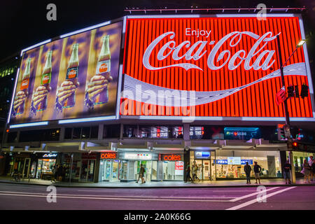Sydney, Australien - 9. März 2017. Die Coca-Cola-Plakatwand in Kings Cross, Sydney, mit Gewerbe und die Menschen, die in der Nacht. Stockfoto