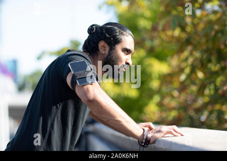 Junge Jogger entspannen und mit einem Smartphone auf den Arm. Stockfoto