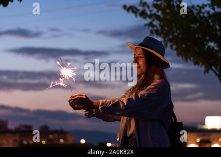 Junge Frau hält ein Funkeln in der Nacht. Freizeitaktivitäten, Feier Stockfoto