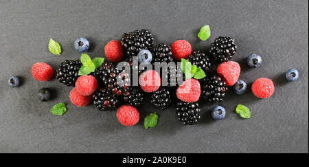 Frische Beeren. Himbeeren, Brombeeren und Heidelbeeren mit Minze auf dunklem Hintergrund. Ansicht von oben Stockfoto