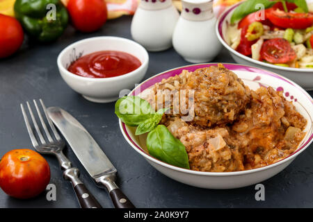 Fleischbällchen in saurer Sahne Sauce und frisches Gemüse Salat in Schalen gegen einen dunklen Hintergrund, horizontale Ausrichtung Stockfoto