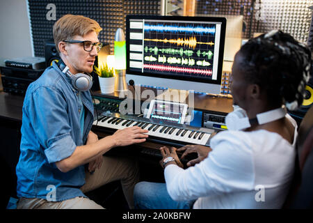 Multi-ethnischen Musiker in casualwear Sitzend durch Arbeitsplatz in Recording Studio Stockfoto