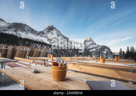 Winterlandschaft mit einem Restaurant im Freien mit Holztischen und schneebedeckten Gipfel der Österreichischen Alpen Berge, im Dezember, in Ehrwald, Österreich. Stockfoto