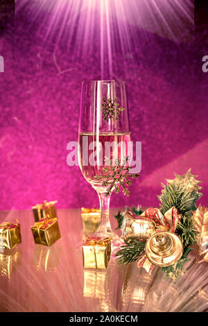 Weihnachtsdekoration und Sektgläser auf lila Hintergrund mit einem Lichtstrahl auf Top Stockfoto