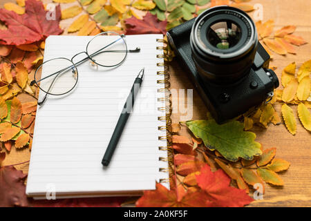 Photocamera, leere Seite von Copybook mit Brille und Stift und Blätter im Herbst Stockfoto