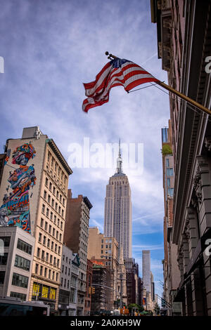 New York Cirt, USA - 31. August 2019: das Empire State Building und die umliegenden Gebäude in Midtown Manhattan mit der USA-Flagge auf der Oberseite Stockfoto