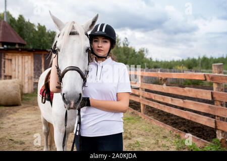 Junge Sportlerin in Activewear ständigen von Weißen reinrassigen rennpferd Stockfoto