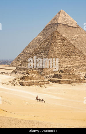 Touristen auf Kamele sehen Khufu, Khafre, Menkaure und Pyramiden von Königinnen aus Wüste. Stockfoto