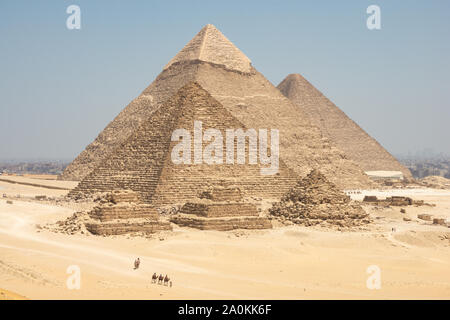 Touristen auf Kamele sehen Khufu, Khafre, Menkaure und Pyramiden von Königinnen aus Wüste. Stockfoto