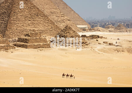 Touristen auf Kamele sehen Khufu, Khafre, Menkaure und Pyramiden von Königinnen aus Wüste. Stockfoto