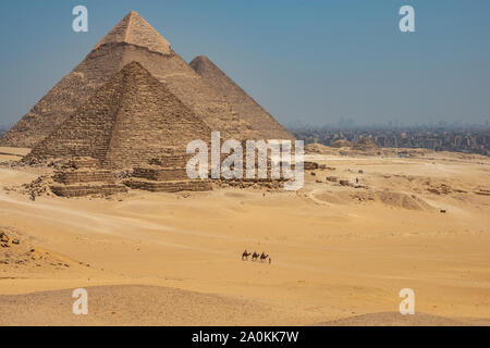 Touristen auf Kamele sehen Khufu, Khafre, Menkaure und Pyramiden von Königinnen aus Wüste. Stockfoto