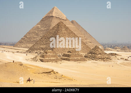 Touristen auf Kamele sehen Khufu, Khafre, Menkaure und Pyramiden von Königinnen aus Wüste. Stockfoto