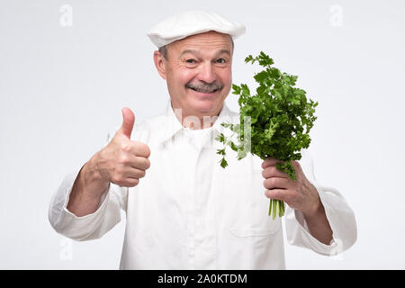 Gesunde Rohkost. und Diäten Konzept. Professionelle Hispanic reifen Koch Küchenchef halten Salat grün. Gesunde vegetarische Rezept Zutaten. Stockfoto