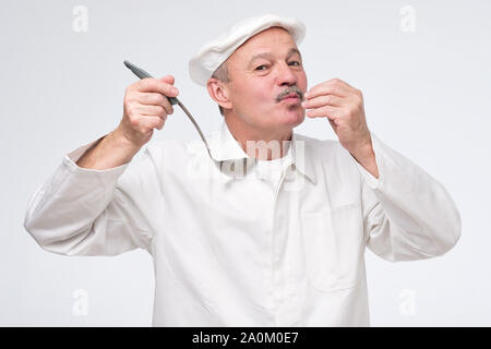 Kochen, Beruf und Menschen anhand von quantitativen Simulatio. Männliche Koch Küchenchef in weiße Uniform Geschmack von Kelle. Studio shot Stockfoto