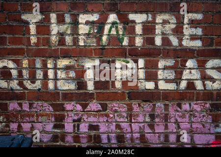 Verblasstes gemaltes Schild an einer roten Ziegelwand, das THEATER RUHIG, mit abgetragenen Schriften und unvollständigen Wörtern darunter liest Stockfoto