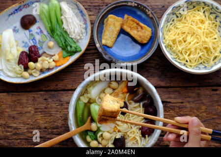 Menschen vegan Essen vietnamesische Nudelsuppe für Frühstück, Vegetarisch hausgemachte Speisen aus Tofu, jujube Obst, Lotus Samen, Bok Choy, Pilz, Spice Stockfoto