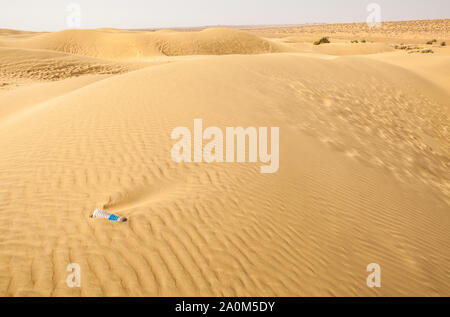 Eine Plastikwasserflasche liegt zur Hälfte in einer Sanddüne in der Wüste Thar der östlichen Rajasthan, Indien begraben. Stockfoto