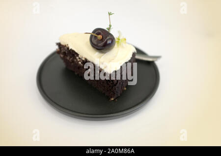 Schwarz Bier Kuchen. Ein Stück schwarzes Kuchen mit Biergeschmack überbacken mit Käse, Sahne und Kirsche Stockfoto