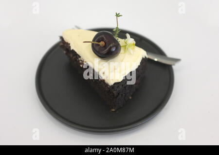 Schwarz Bier Kuchen. Ein Stück schwarzes Kuchen mit Biergeschmack überbacken mit Käse, Sahne und Kirsche Stockfoto