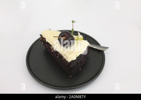 Schwarz Bier Kuchen. Ein Stück schwarzes Kuchen mit Biergeschmack überbacken mit Käse, Sahne und Kirsche Stockfoto