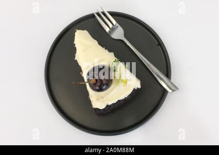 Schwarz Bier Kuchen. Ein Stück schwarzes Kuchen mit Biergeschmack überbacken mit Käse, Sahne und Kirsche Stockfoto