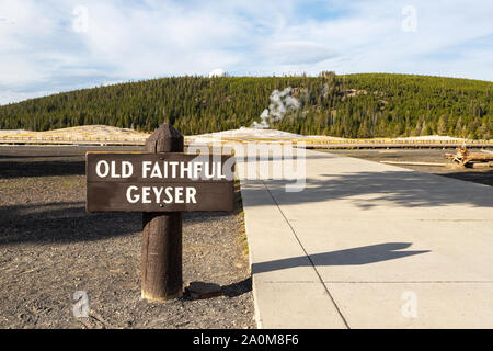 Old Faithful Geyser Zeichen des Yellowstone National Park mit Dampf, der aus dem Geysir im Hintergrund. Stockfoto