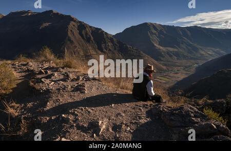 Pisac, Peru - 11. August 2011: ein Mann sitzt auf der Kante des Berges. Stockfoto