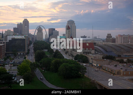 Der Gateway Arch erhebt sich bei Sonnenaufgang über der Skyline von St Louis, wobei das historische Gebäude der Union Station im Vordergrund steht. Stockfoto