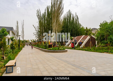 Hotan malerischen Kunlun Lake Park Blick auf Blume Gasse mit Bänken, Bäumen und wenige Leute an einem bewölkten Himmel Tag Stockfoto