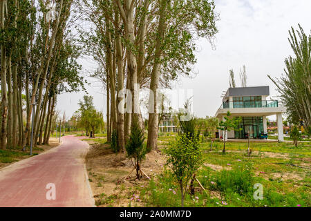 Hotan malerischen Kunlun Lake Park Blick auf einen gemeinsamen Weg mit Bäumen und Häusern an einem bewölkten Himmel Tag Stockfoto