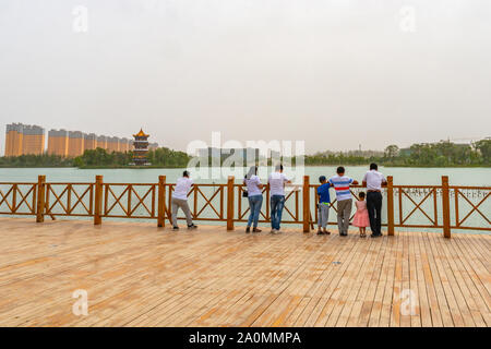 Hotan malerischen Kunlun Park Holzterrasse mit Zuschauen Menschen lehnte sich auf Zaun und atemberaubenden Seeblick an einem bewölkten Himmel Tag Stockfoto