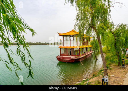 Hotan malerischen Kunlun Lake Park Blick auf einen Verankerten chinesisches Schiff am Ufer an einem bewölkten Himmel Tag Stockfoto