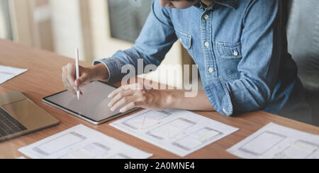 7/8-Ansicht von UX Web Developer zeichnen das Smartphone Vorlagen auf Tablet in modernen Büro Zimmer Stockfoto