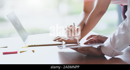 Young Professional UI Graphic Designer diskutieren auf ihren Smartphones Vorlagen während der Verwendung von Tablet Stockfoto