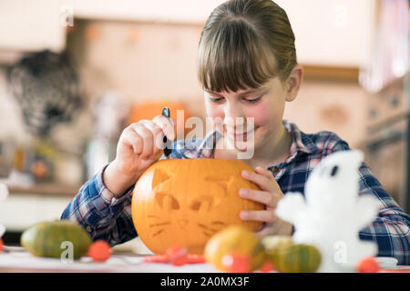 Mädchen schnitzen Halloween Laterne aus Kürbis zu Hause Stockfoto