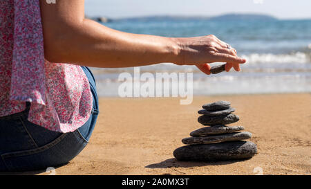 Nahaufnahme von Realxed Frau Stapeln Steine auf ruhigen Strand Ferienhäuser Stockfoto