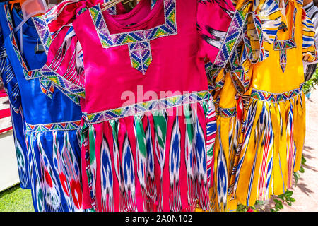 Kashgar traditionellen Uigurischen Blau Rosa und Gelb gefärbten Kleider für kleine Mädchen in einem Bekleidungsgeschäft Stockfoto